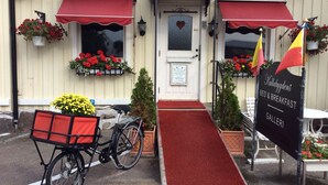 A building with a red awning, a bicycle, and a sign indicating it is a bed and breakfast. - Kullabygdens Bed & Breakfast (Jonstorp)