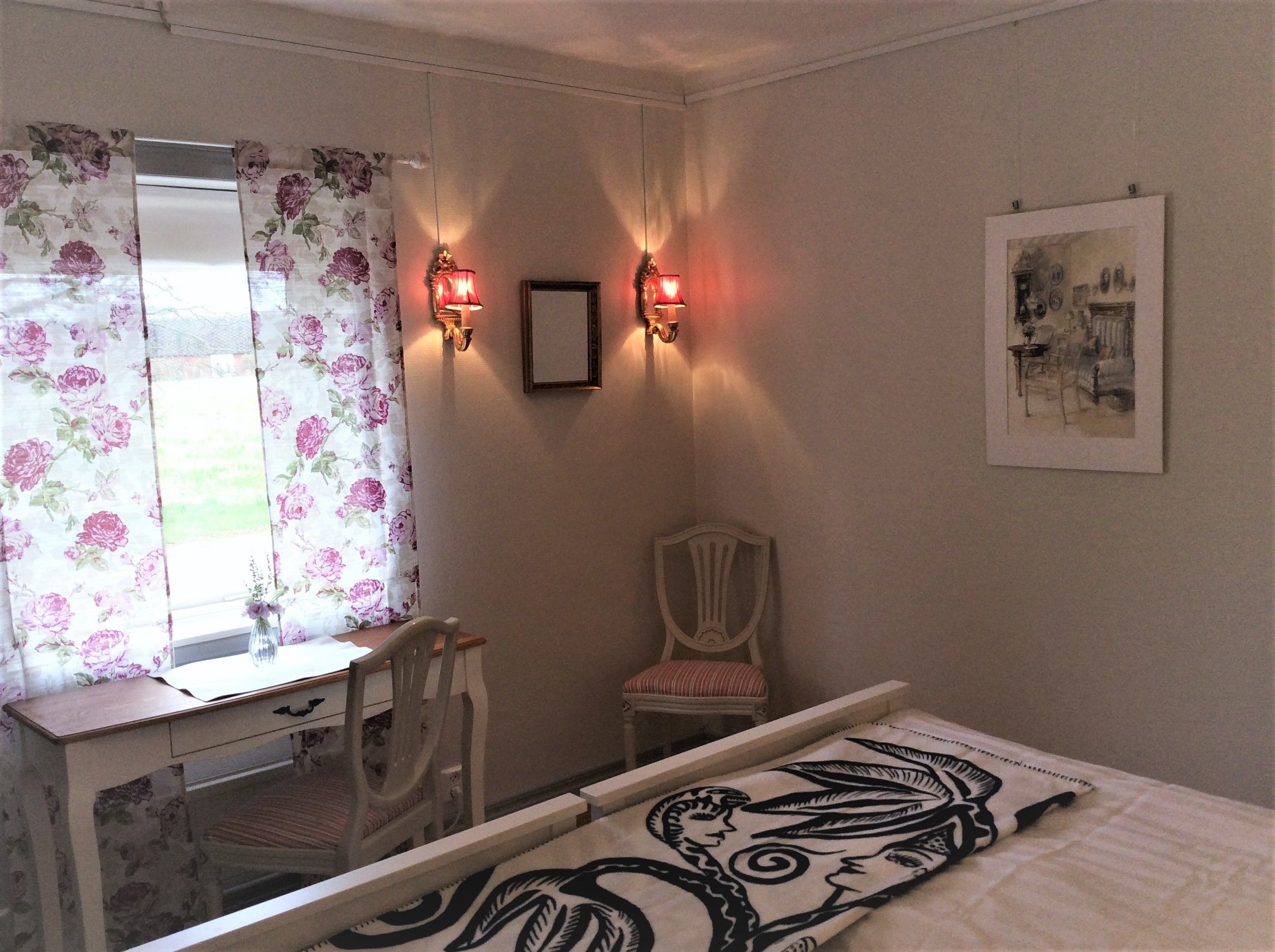 Un dormitorio con cama, escritorio, silla, espejo e iluminación en la pared.