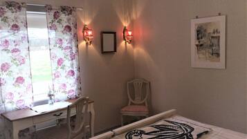 Un dormitorio con cama, escritorio, silla, espejo e iluminación en la pared.