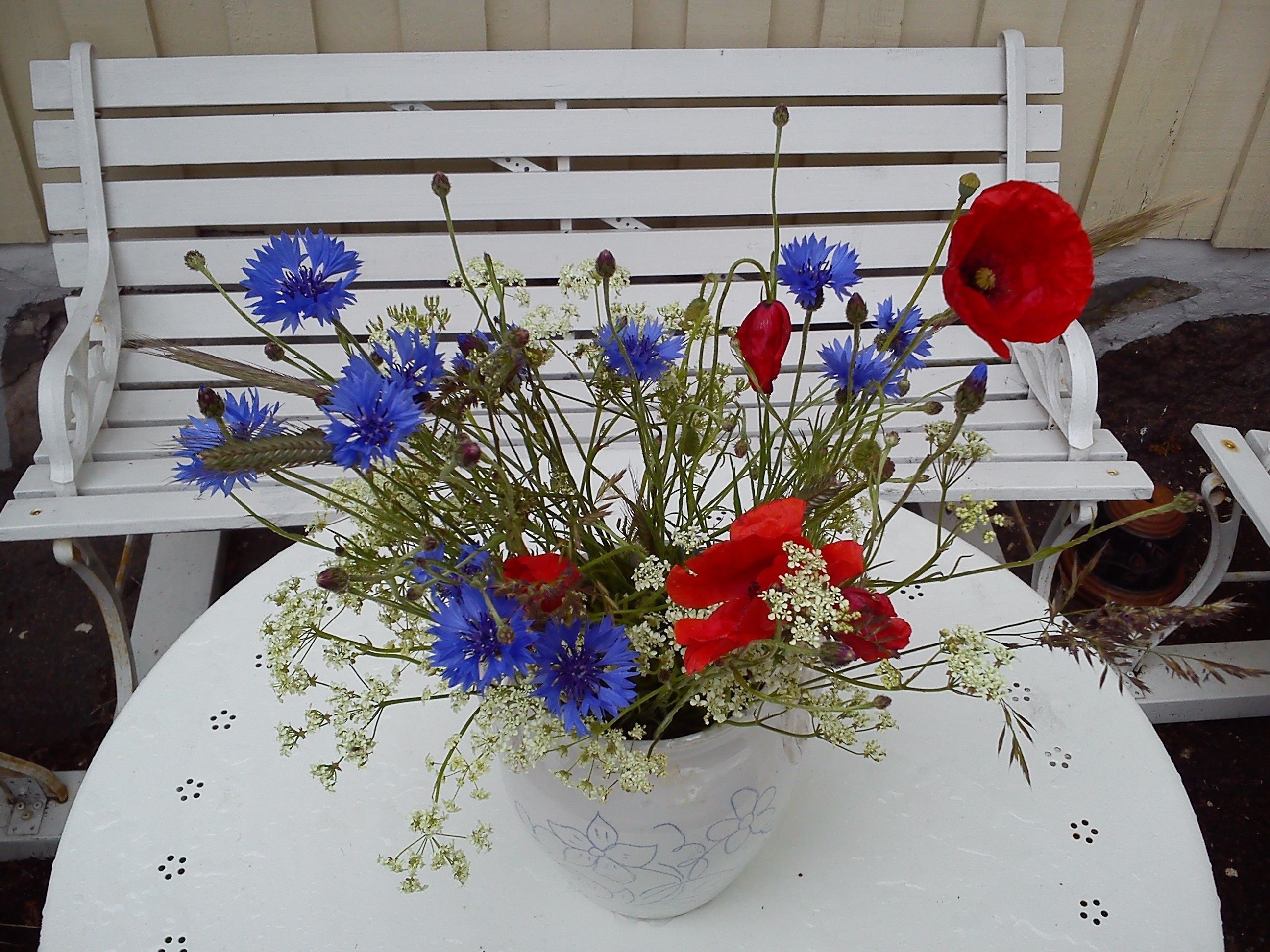 A white table with a floral arrangement in a decorative bowl.