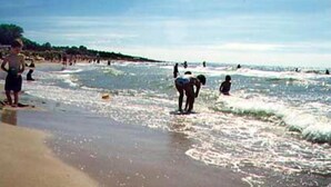 A beach with people standing and walking in the water. - Kullabygdens Bed & Breakfast (Jonstorp)
