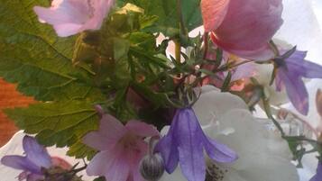 Ein Blumenstrauß mit rosa, violett und weißen Blüten, grünen Blättern und einem sichtbaren Stiel.