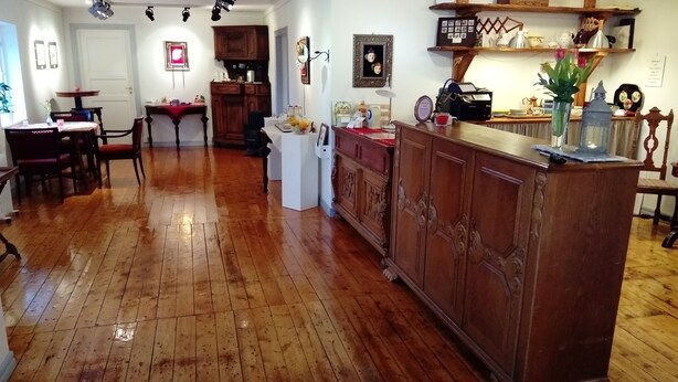 A spacious kitchen with wooden flooring, a central island, and a dining area with chairs and a table. - Kullabygdens Bed & Breakfast (Jonstorp)