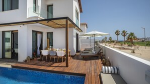 A modern house with a pool, outdoor seating, and a view of the beach. - Chris Le Mare Luxury Villa By Louis Hotels (Paralimni)