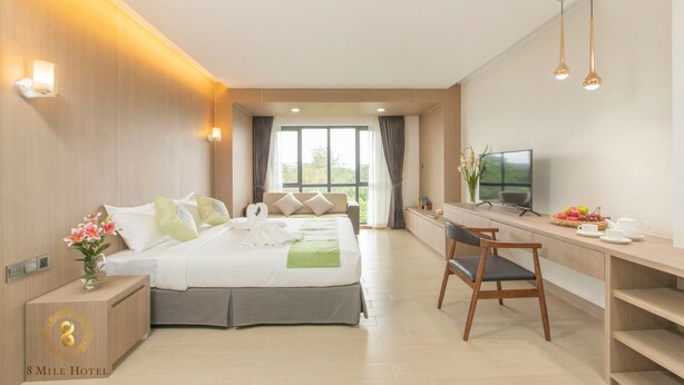 Habitación de hotel con cama, escritorio, televisor y vista a zonas verdes.