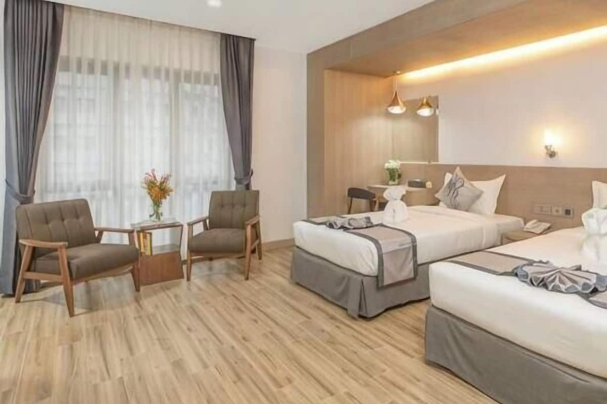 A hotel room with two beds, a desk, and a chair.