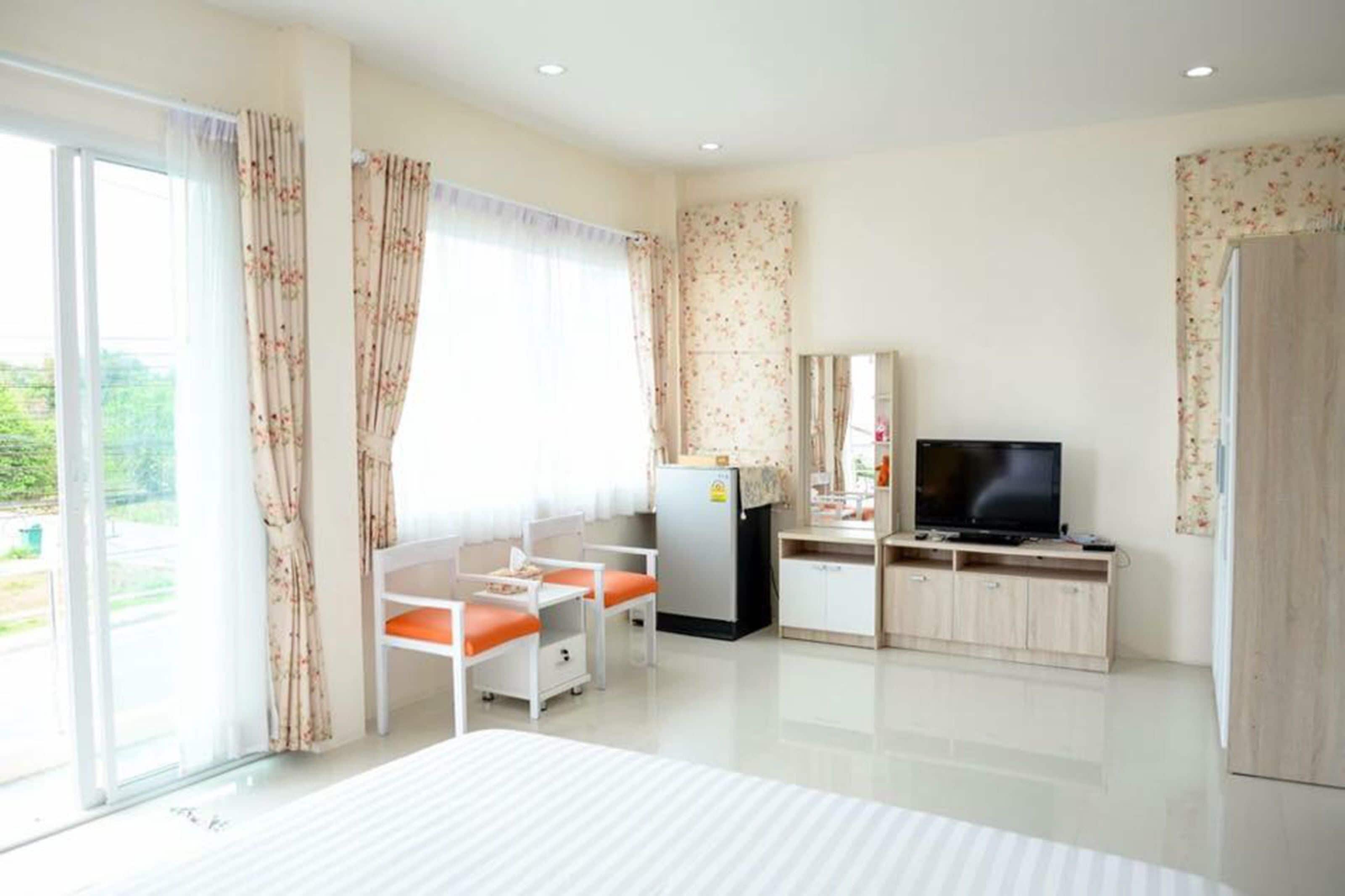 A hotel room with a bed, a TV, a desk with a chair, a refrigerator, and a wardrobe.
