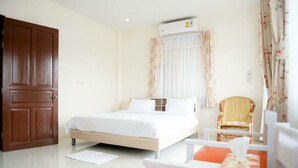 A bedroom with a bed, a chair, a table, a door, and an air conditioning unit. - Baanmeerak at Ranong (Ranong)