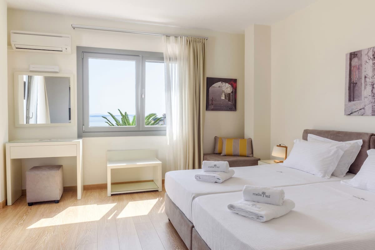 A hotel room with a bed, bedside tables, a desk, and a window with curtains.