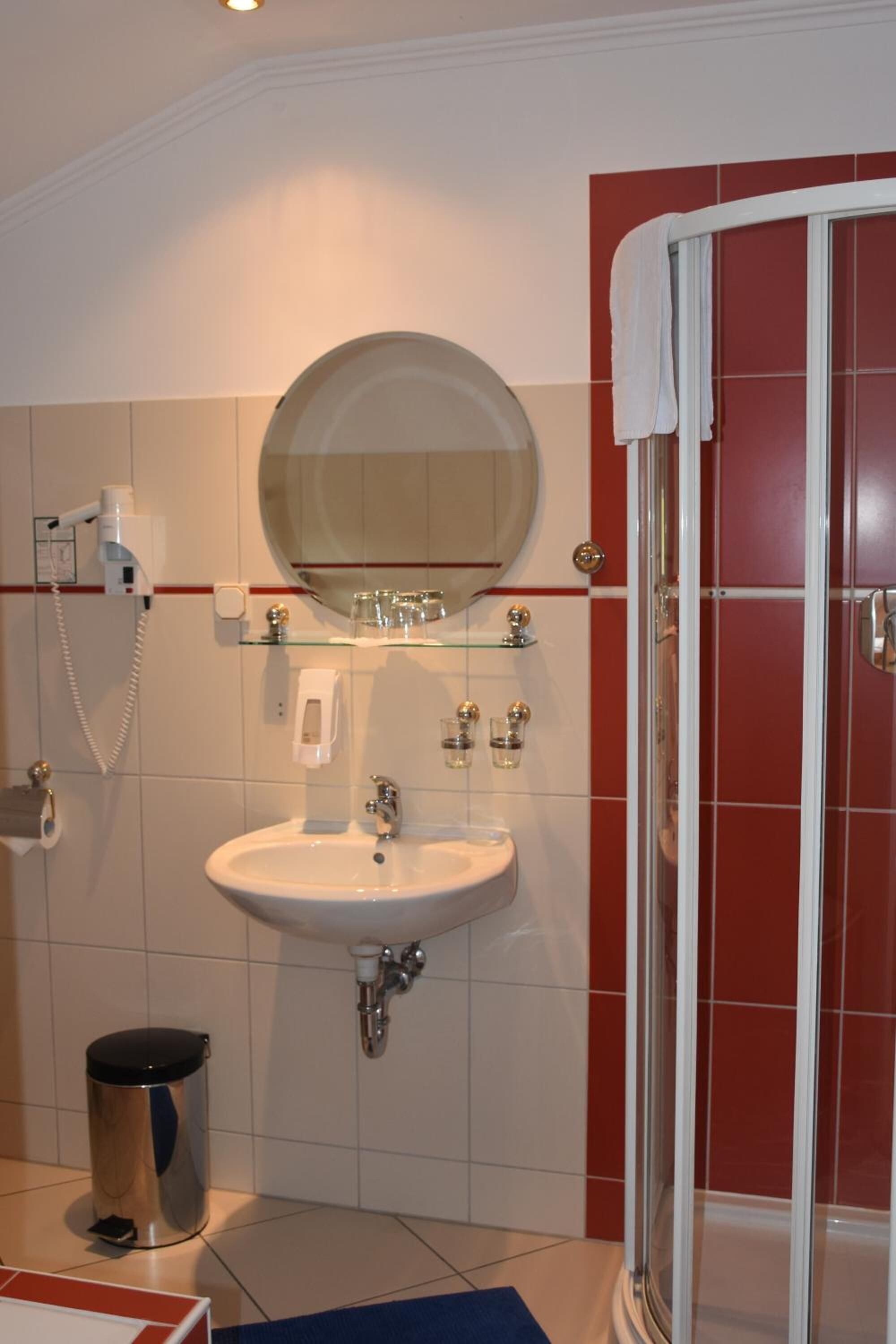 A bathroom with a sink, mirror, and shower.
