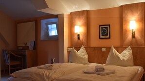 Habitación de hotel con una cama grande, dos lámparas de noche, un escritorio con una silla y un cuadro en la pared.