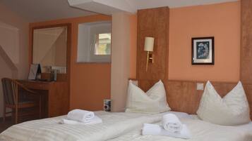 Habitació d'hotel amb dos llits, una taula, una cadira, una làmpada i un quadre al mur.
