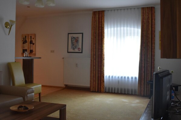 A living room with a sofa, a coffee table, a television, and a radiator.