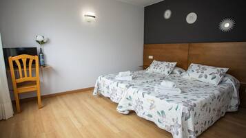 Ein Schlafzimmer mit Doppelbett, einem Holzstuhl, einem Schreibtisch und einem Fernseher.