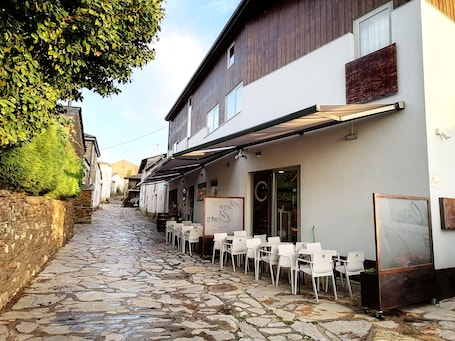A cobblestone street with outdoor seating and a building with a wooden facade.