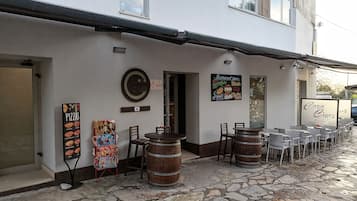 Un restaurante con terraza, suelo de piedra y cartel con la carta.