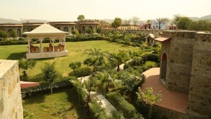 A courtyard with a gazebo, stone buildings, and lush greenery. - Van Chhavi Resort (Rajgarh)