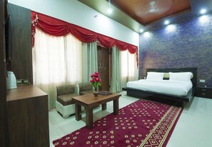 A hotel room with a bed, a desk, a chair, a coffee machine, and a vase with flowers. - Van Chhavi Resort (Rajgarh)