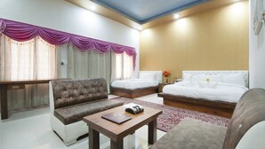 A hotel room with a sofa, a bed, a small table, and a nightstand. - Van Chhavi Resort (Rajgarh)