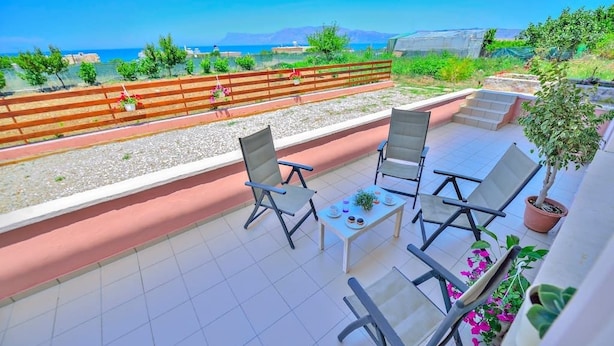A balcony with a table and chairs, a potted plant, and a view of the sea. - Eliana (Kissamos)