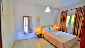 A bedroom with a bed, bedside lamps, a chair, a mirror, and curtains. - Eliana (Kissamos)