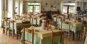A dining area with multiple tables and chairs, arranged in rows. - Albergo Sargas (Cevo)