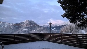 A snow-covered bench with a view of snow-capped mountains and a string of lights in the background. - Albergo Sargas (Cevo)
