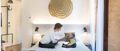 A room with a bed, a circular wall hanging, and a small table with a lamp.