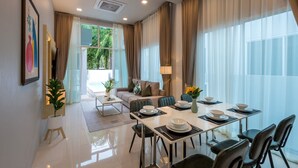 A modern hotel room with a dining area, a sofa, a coffee table, and a large window with curtains. - The Haven Krabi (Krabi)