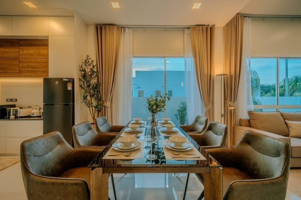 Un comedor moderno con una mesa de vidrio dispuesta para seis personas, rodeada de sillas de cuero.