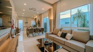 A modern living room with a sofa, coffee table, and dining area. - The Haven Krabi (Krabi)