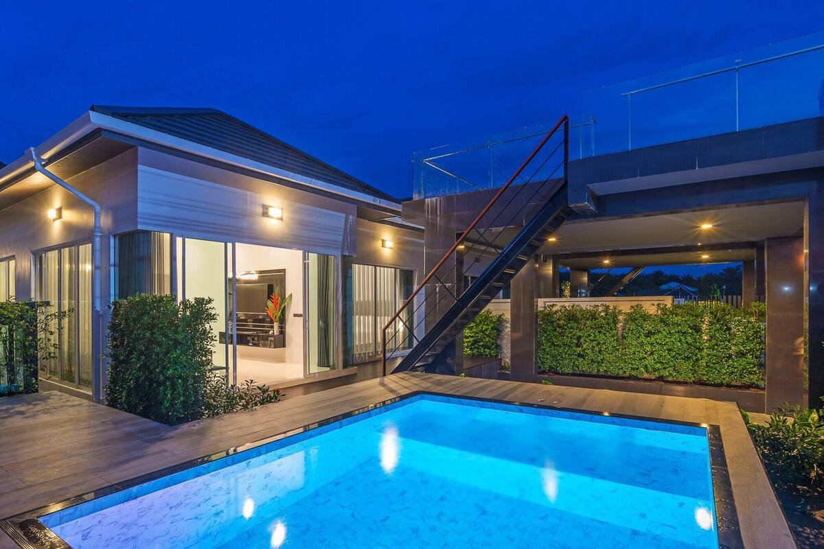 A modern house with a swimming pool, a covered patio, and a staircase leading to an upper level.