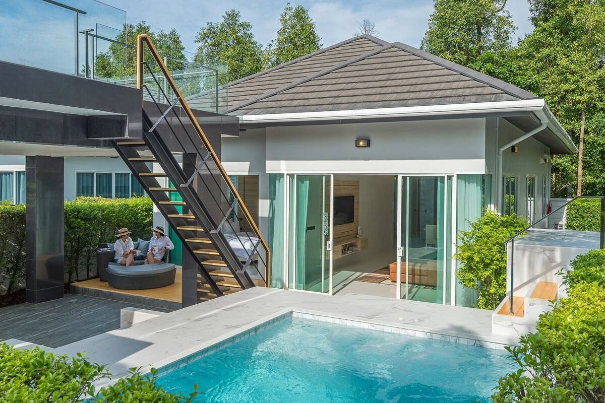 A modern house with a pool, a staircase, and a glass door leading to a living area.