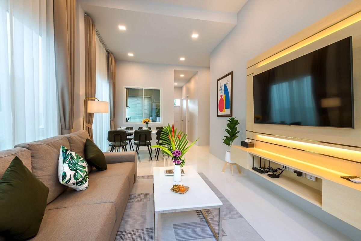 A modern living room with a sofa, coffee table, TV, and dining area.