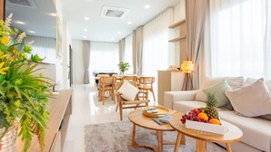 A modern living room with a sofa, coffee table, and dining area. - The Haven Krabi (Krabi)