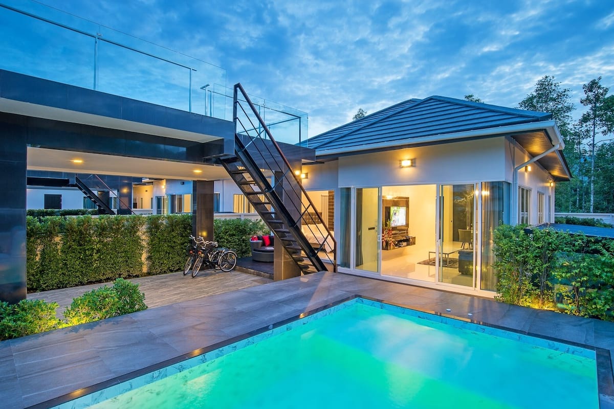 A modern house with a swimming pool, a staircase, and a glass door leading to a patio area.