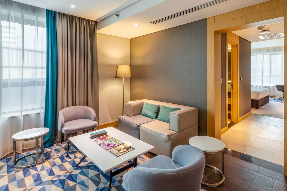 Une chambre d’hôtel moderne, dotée d’un canapé, de fauteuils, d’une table basse et d’un tapis à motifs.