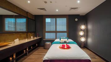Relax in a serene space with a large massage table, a dark-colored bench, and a mirror, set against a stunning view.