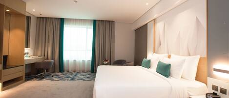 A modern hotel room with a large bed, a desk, and a chair.