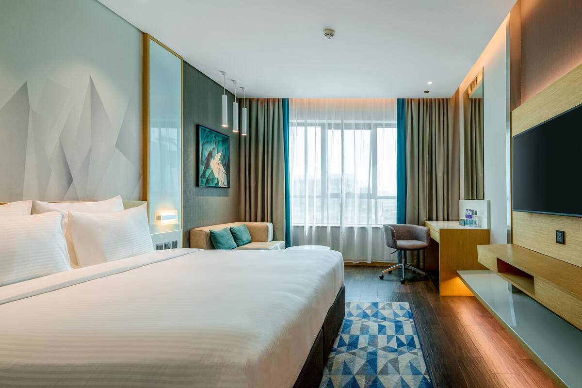Une chambre d’hôtel moderne équipée d’un grand lit, d’un bureau, d’une chaise et d’un téléviseur.