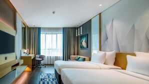 Une chambre d’hôtel avec deux lits, un bureau, une chaise, une télévision et une grande fenêtre avec des rideaux.