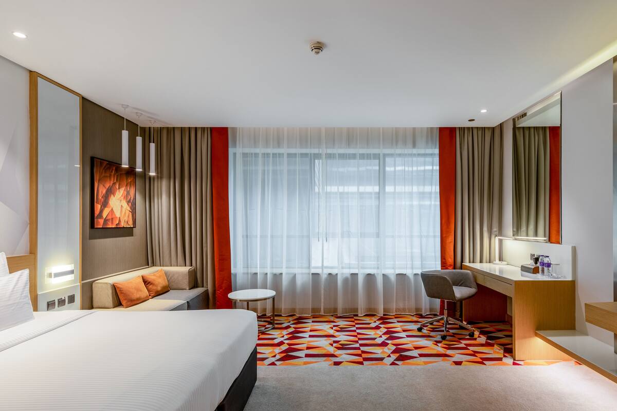 Une chambre d’hôtel avec un grand lit, un bureau, une chaise et une petite table.