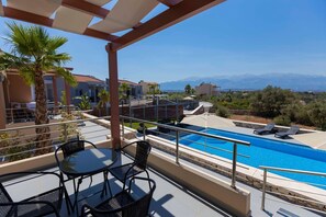 A rooftop pool area with a clear view of mountains, a palm tree, and a covered seating area with chairs. - Electra Villas at Kokkino Chorio (Apokoronas)
