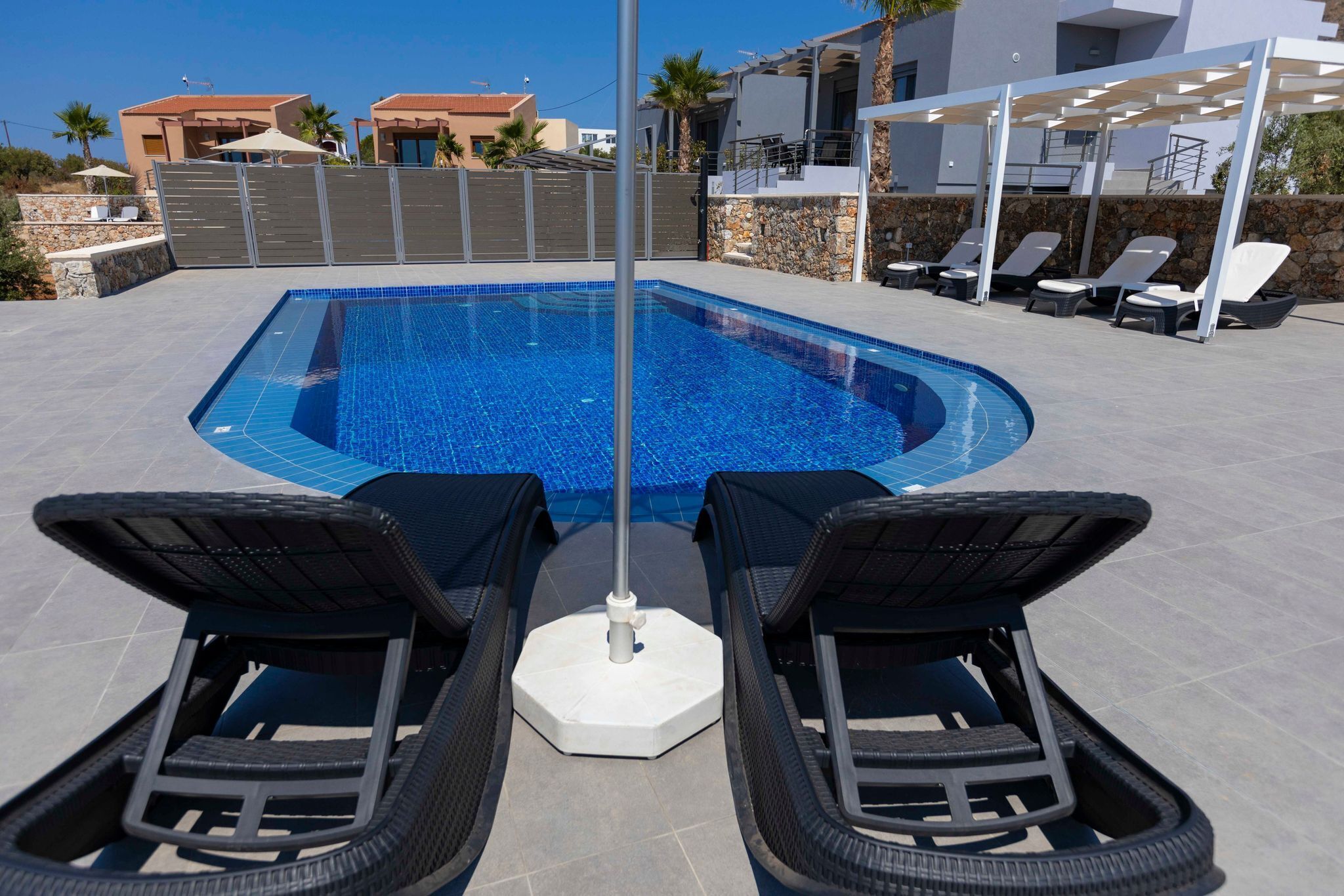 Une piscine avec des chaises longues et un mur en pierre.