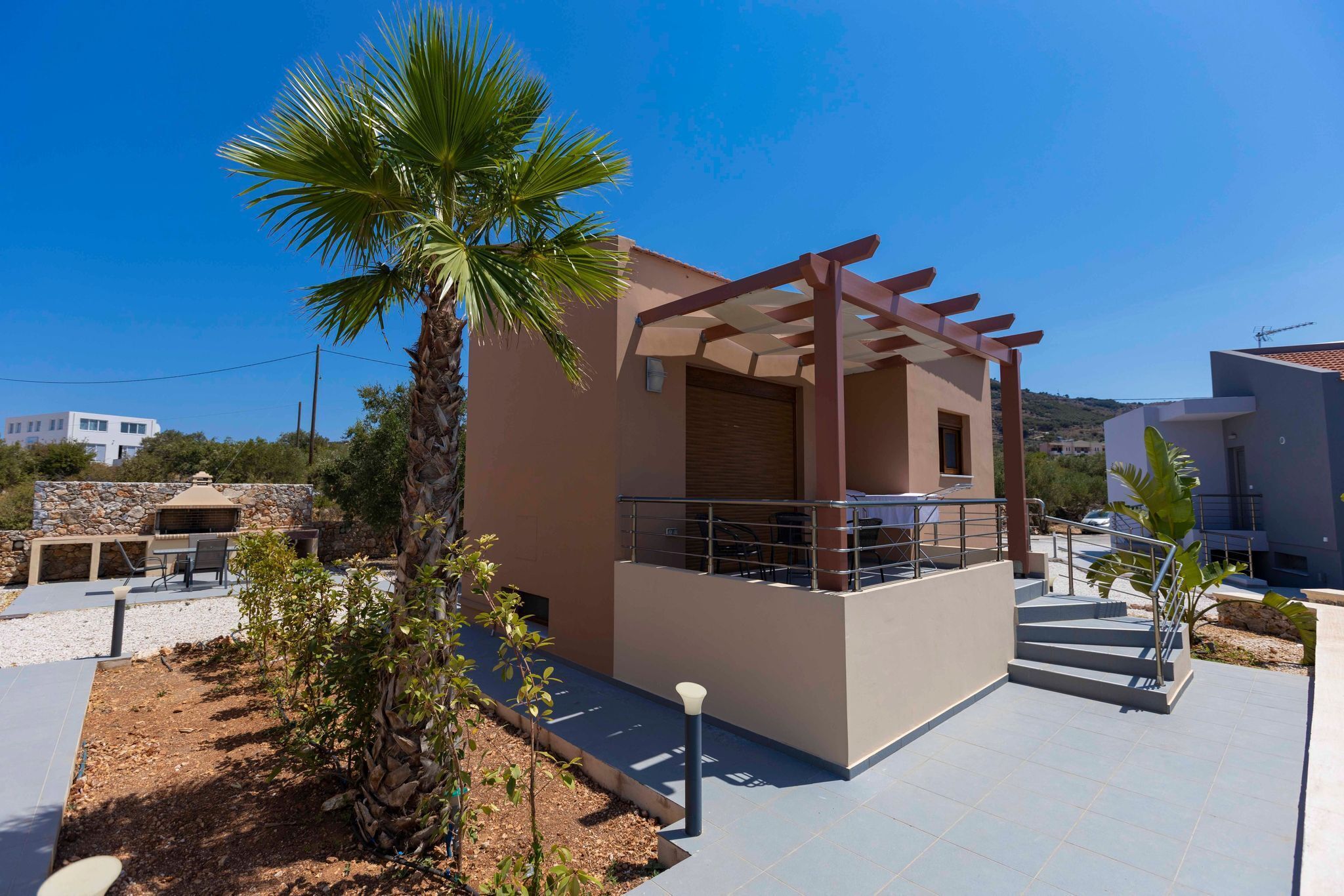 A modern house with a patio, a pergola, and a palm tree.