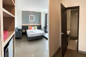 A modern hotel room with a bed, bedside table, and a view of the bathroom. - Clover Hotel Hatyai (Hat Yai)