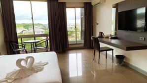 Una habitación de hotel con cama, escritorio, silla, televisor y vistas a la ciudad.