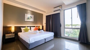 Una habitación de hotel moderna con una cama grande, una mesita de noche, aire acondicionado instalado en la pared y una ventana con cortinas.