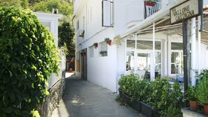 Une rue étroite, avec un bâtiment blanc sur la gauche et un magasin sur la droite.