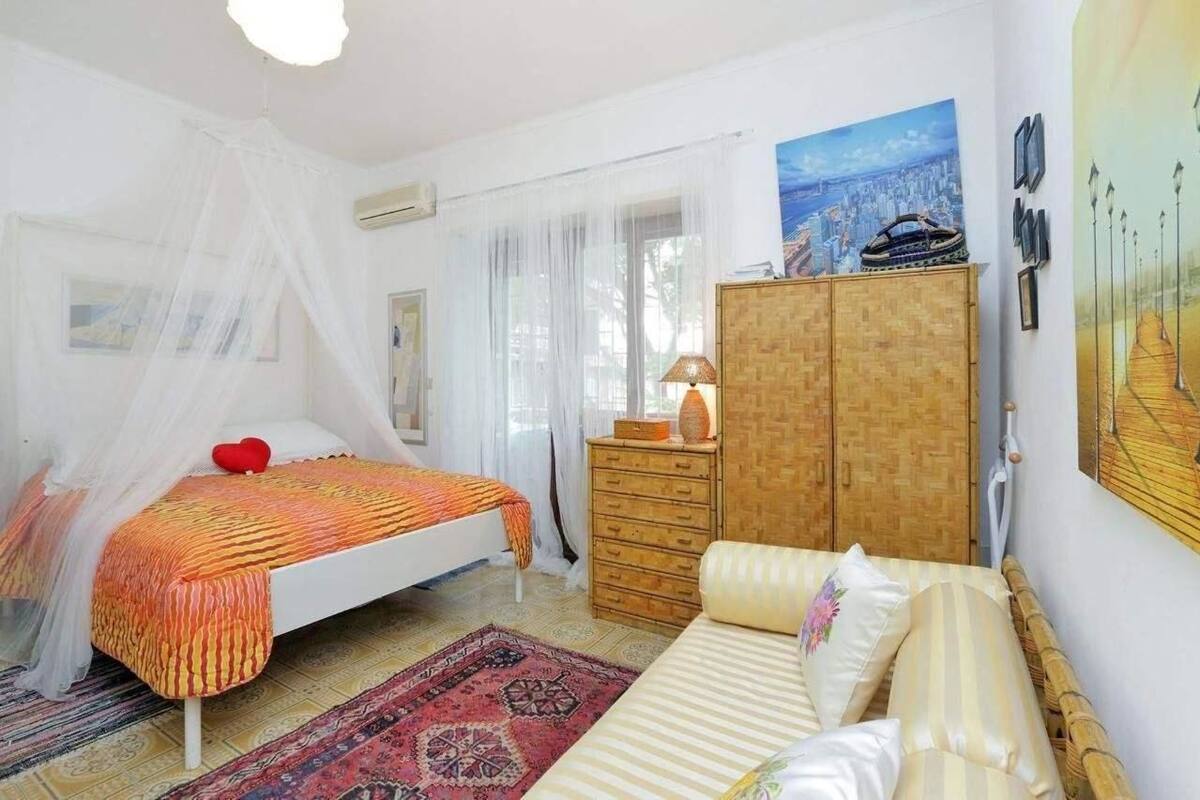 A bedroom with a bed, a sofa, a wardrobe, and a painting on the wall.